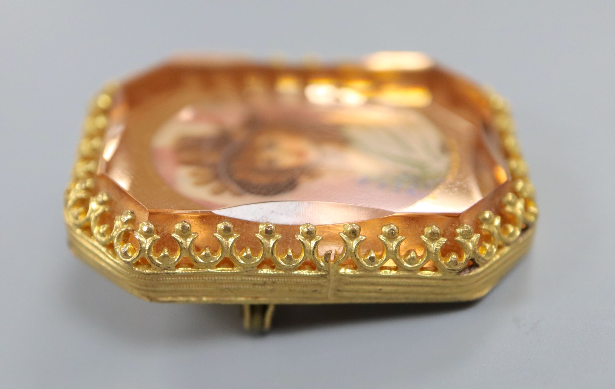 A yellow metal mounted octagonal brooch, with oval painted bust of a lady in mirrored surround, 36mm, gross 16.8 grams.
